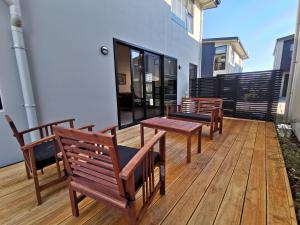 eine Terrasse mit Bänken und Tischen auf einem Haus in der Unterkunft Nelson City Town House 10 minute walk to town in Nelson