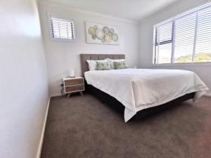 a white bedroom with a large bed and a window at Nelson City Town House 10 minute walk to town in Nelson