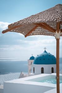 a umbrella sitting on top of a table next to a church at Cilon Suites Santorini in Imerovigli