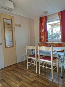 uma sala de jantar com uma mesa e cadeiras e uma janela em Bungalow des amis em Le Grau-du-Roi