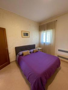 een paars bed in een kamer met een raam bij Casa Mediterranea: appartamento vista mare a soli 200m dalla spiaggia in Sperlonga