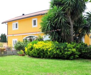 a yellow house with a palm tree in a yard at Appartamento in villa al mare in Siracusa