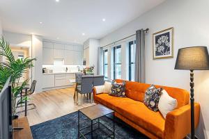 a living room with an orange couch and a kitchen at Gorgeous Roehampton Flat in London