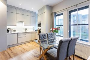 uma cozinha com armários brancos e uma mesa e cadeiras em Gorgeous Roehampton Flat em Londres