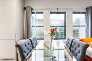 uma sala de estar com uma mesa de vidro e 2 cadeiras em Gorgeous Roehampton Flat em Londres