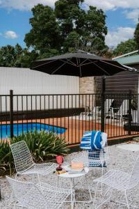 a table and chairs with an umbrella next to a pool at 'Mortimer Gardens' Country Charm in the Heart of Mudgee in Mudgee