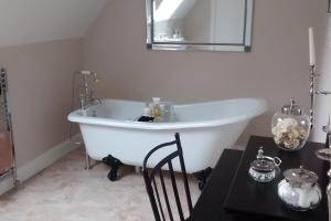 bañera blanca en una habitación blanca con mesa en 7 Burnside House, en Kilmorack
