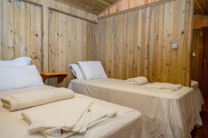 two beds in a room with wooden walls at Tree Houses Hotel in Fethiye