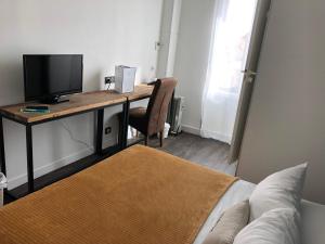 a room with a desk with a television and a bed at Hôtel Restaurant L'Atelier des Cousins in Châtelaillon-Plage