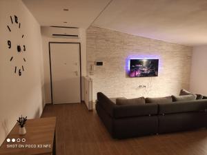 sala de estar con sofá y TV en una pared de ladrillo en Casa vacanze Marinella, en Cetraro