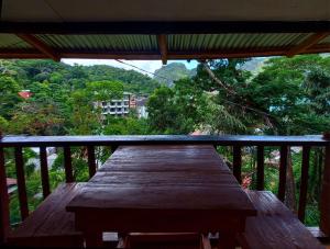 una mesa de madera en un balcón con vistas a los árboles en BaleCabugaoCottagesRental en El Nido