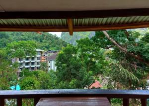 愛妮島的住宿－BaleCabugaoCottagesRental，从树木繁茂的建筑的阳台上可欣赏到风景