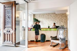 a woman standing at a counter with her luggage at Hotel Lorette - Astotel in Paris