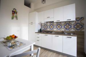 a kitchen with white cabinets and a bowl of fruit on a table at La Paranza Apartments Lampedusa in Lampedusa