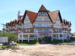 a large brown building with a car parked in front of it at Gemelos Apart in Villa Gesell