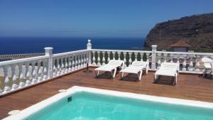 a deck with chairs and a swimming pool with the ocean at Apartamentos Isa in Tazacorte