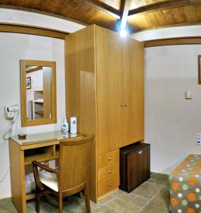 een kamer met een bureau, een bed en een spiegel bij TARLAS ROOMS in Mytilini