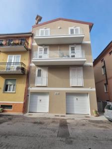 a tall building with four white garage doors at Appartamenti nuovi in centro a Porto Recanati Riviera del Conero in Porto Recanati