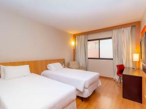 um quarto de hotel com duas camas e uma janela em Novotel Campo Grande em Campo Grande