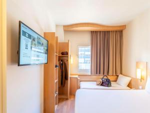 a hotel room with two beds and a flat screen tv at Ibis Madrid Calle Alcalá in Madrid