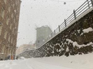 a snow storm in a city with buildings and a sidewalk at Spacious (44 sqm) bohemian studio in trendy Kallio in Helsinki