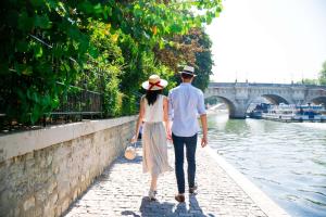 a man and a woman walking along a canal at Hôtel du Louvre, in The Unbound Collection by Hyatt in Paris