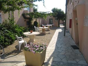 een patio met tafels, stoelen en bloemen op een stoep bij Hotel La Reserve in Vic-la-Gardiole