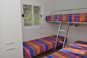um beliche com uma escada ao lado de uma janela em Family Wellness Camping al Sole em Molina di Ledro
