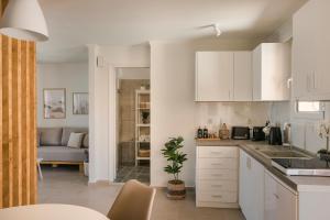 eine Küche mit weißen Schränken und ein Wohnzimmer in der Unterkunft Theseus Seafront House in Sami
