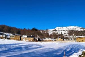 um campo coberto de neve com casas e uma montanha em O Busto Aldea Rural 