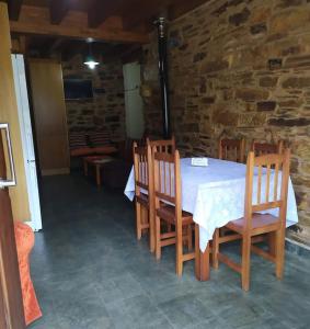 a table and chairs in a room with a stone wall at O Busto Aldea Rural 
