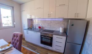a kitchen with white cabinets and a stainless steel refrigerator at Elegant Avenue Escape in Mostar
