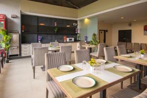a dining room with tables and chairs and a kitchen at Octave Koregaon Park in Pune