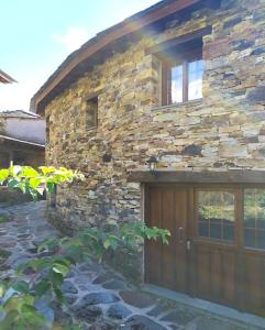 a stone house with a wooden garage door at O Busto Aldea Rural 