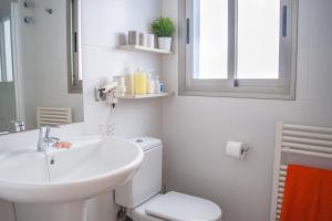 a bathroom with a sink and a toilet and a mirror at Apartamentos Marfina in Castelldefels