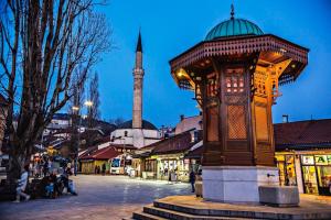 a clock tower in a city with a mosque in the background at Apartment BERINA in Sarajevo