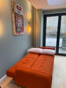 a large orange couch in a room with a window at 1 Bed Garden Flat Finsbury Park in London