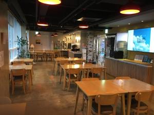 a restaurant with tables and chairs and a large screen at Hotel Rest Seogwipo in Seogwipo