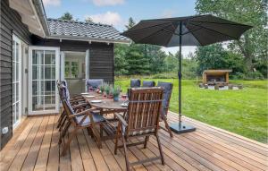 eine Holzterrasse mit einem Tisch und einem Sonnenschirm in der Unterkunft Cozy Home In Aakirkeby With Kitchen in Vester Sømarken
