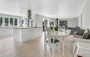 eine weiße Küche mit einem Tisch und einem Sofa in der Unterkunft Cozy Home In Aakirkeby With Kitchen in Vester Sømarken