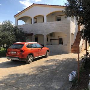 a red car parked in front of a house at Apartments Marija in Vir