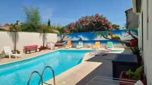 a swimming pool with chairs and a painting on the wall at chambre chez corinne et bernard in Cazouls-lès-Béziers +1 photo