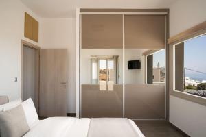 1 dormitorio con cama blanca y pared de cristal en In the heart of Fira & free pool - Nychteri suite, en Fira