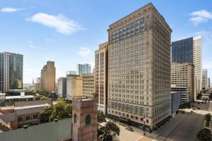 ein hohes Gebäude mit einem Uhrturm in einer Stadt in der Unterkunft Magnolia Hotel Houston, a Tribute Portfolio Hotel in Houston