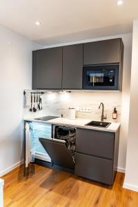 a kitchen with black cabinets and a sink at NUVA Apartments in Cologne