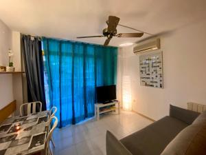 sala de estar con sofá y TV en Apartamento con servicios, piscina y parking privado máx 4 pax, en Salou