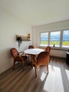 a dining room with a table and chairs and two windows at Helles Ferienhaus Storchenblick in Buchholz Aller