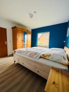 a bedroom with a large bed with a blue wall at Helles Ferienhaus Storchenblick in Buchholz Aller