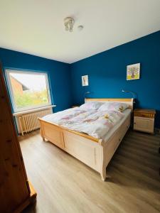 a bedroom with a wooden bed in a blue wall at Helles Ferienhaus Storchenblick in Buchholz Aller