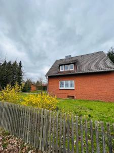 a red brick house with a fence in front of it at Helles Ferienhaus Storchenblick in Buchholz Aller